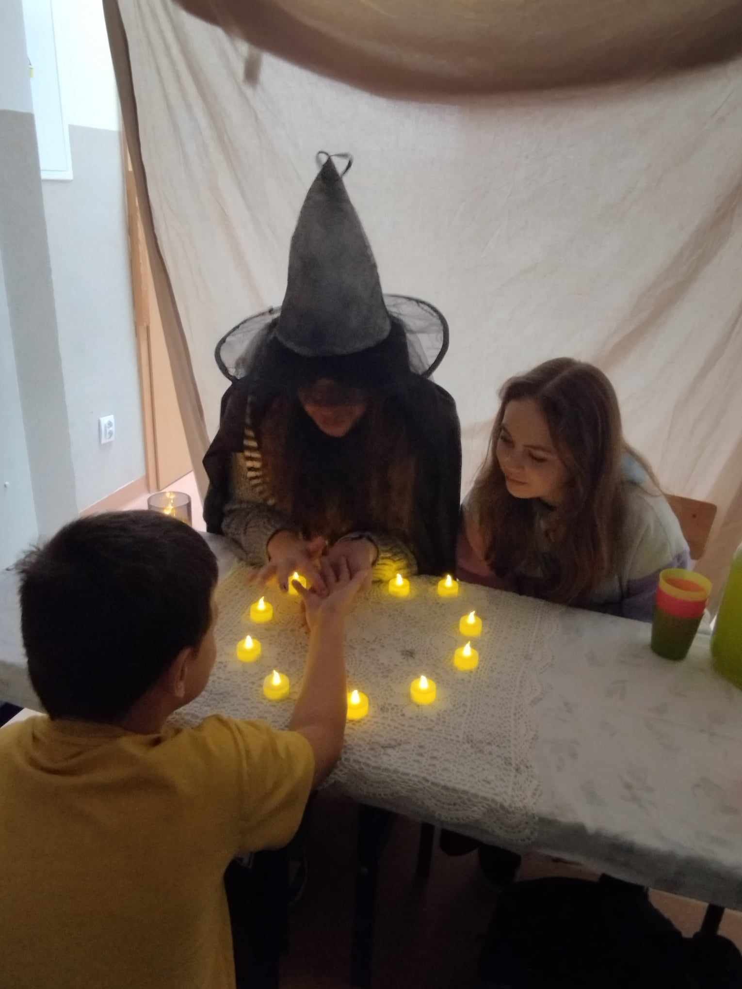 Dzieci siedzą przy stole, jedna osoba jest przebrana za wróżkę