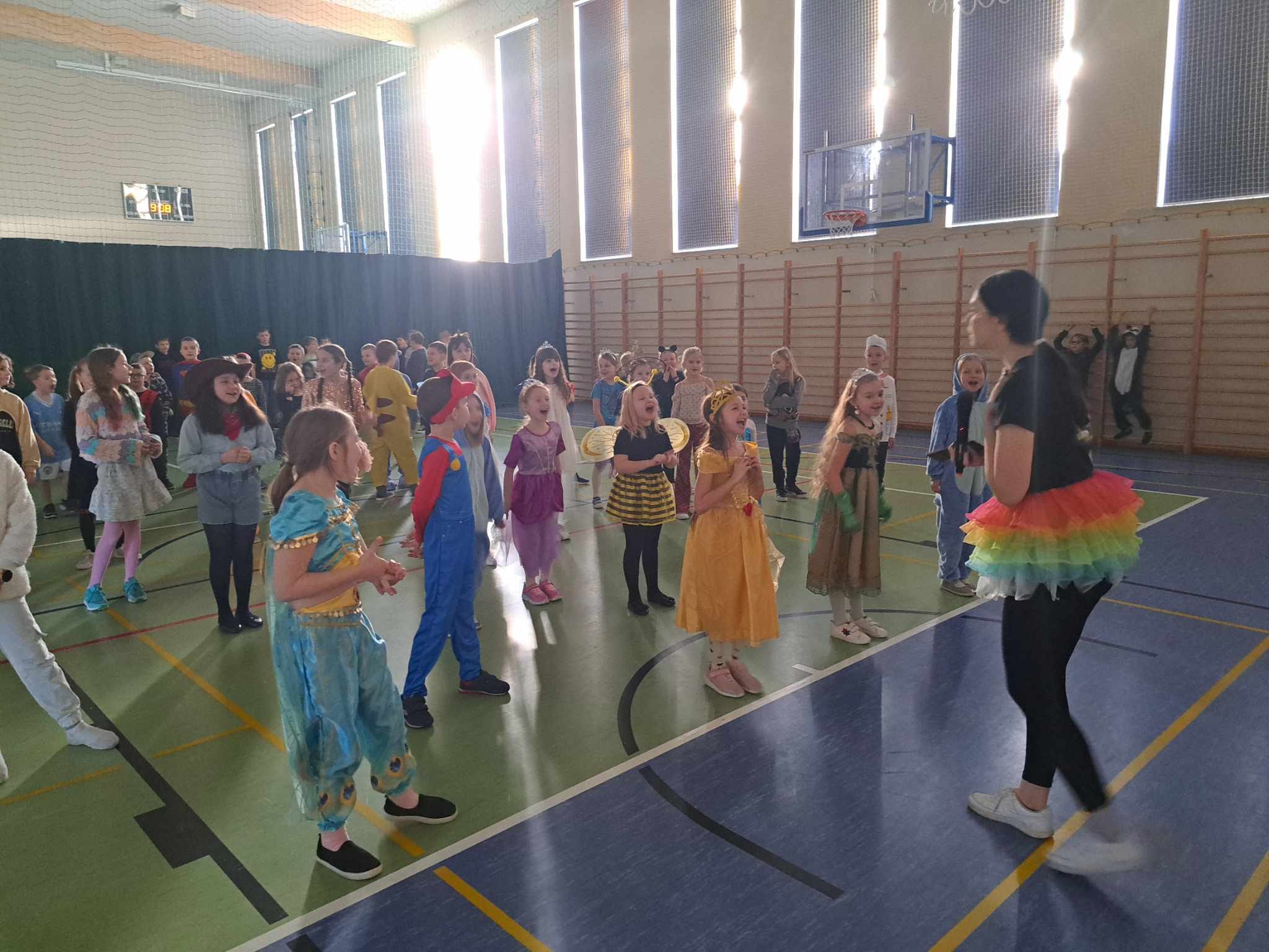 Dzieci w strojach karnawałowych tańczą na sali gimnastycznej