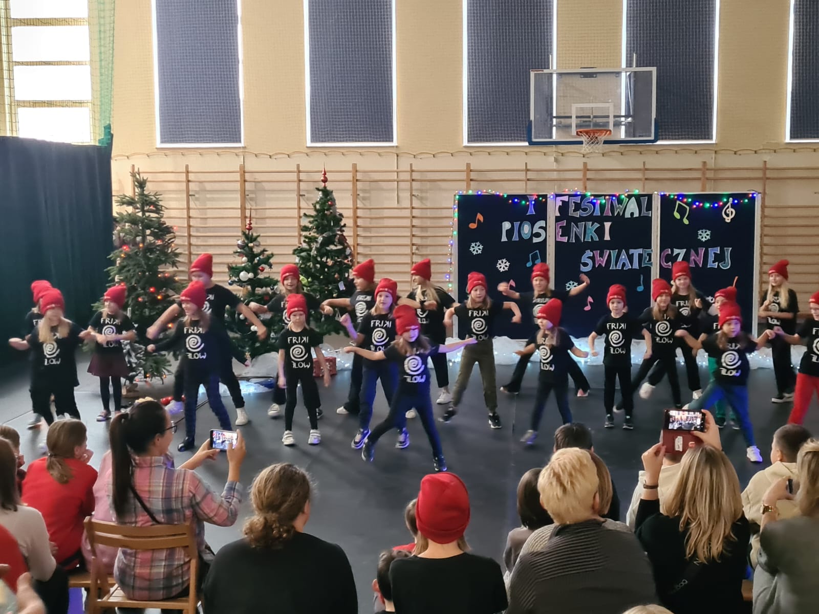 Dzieci występują na tle dekoracji świątecznej