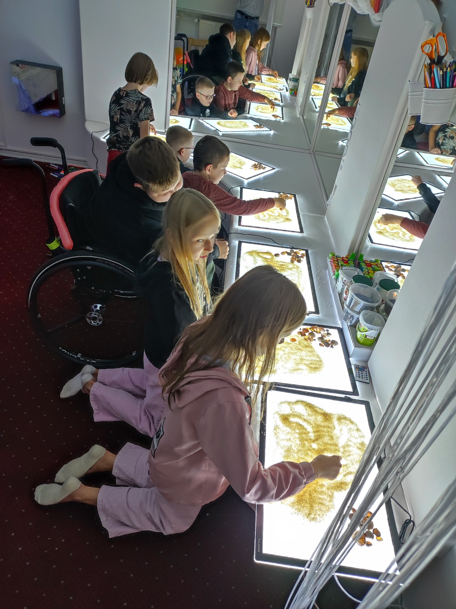 Dzieci w sali malują w piasku