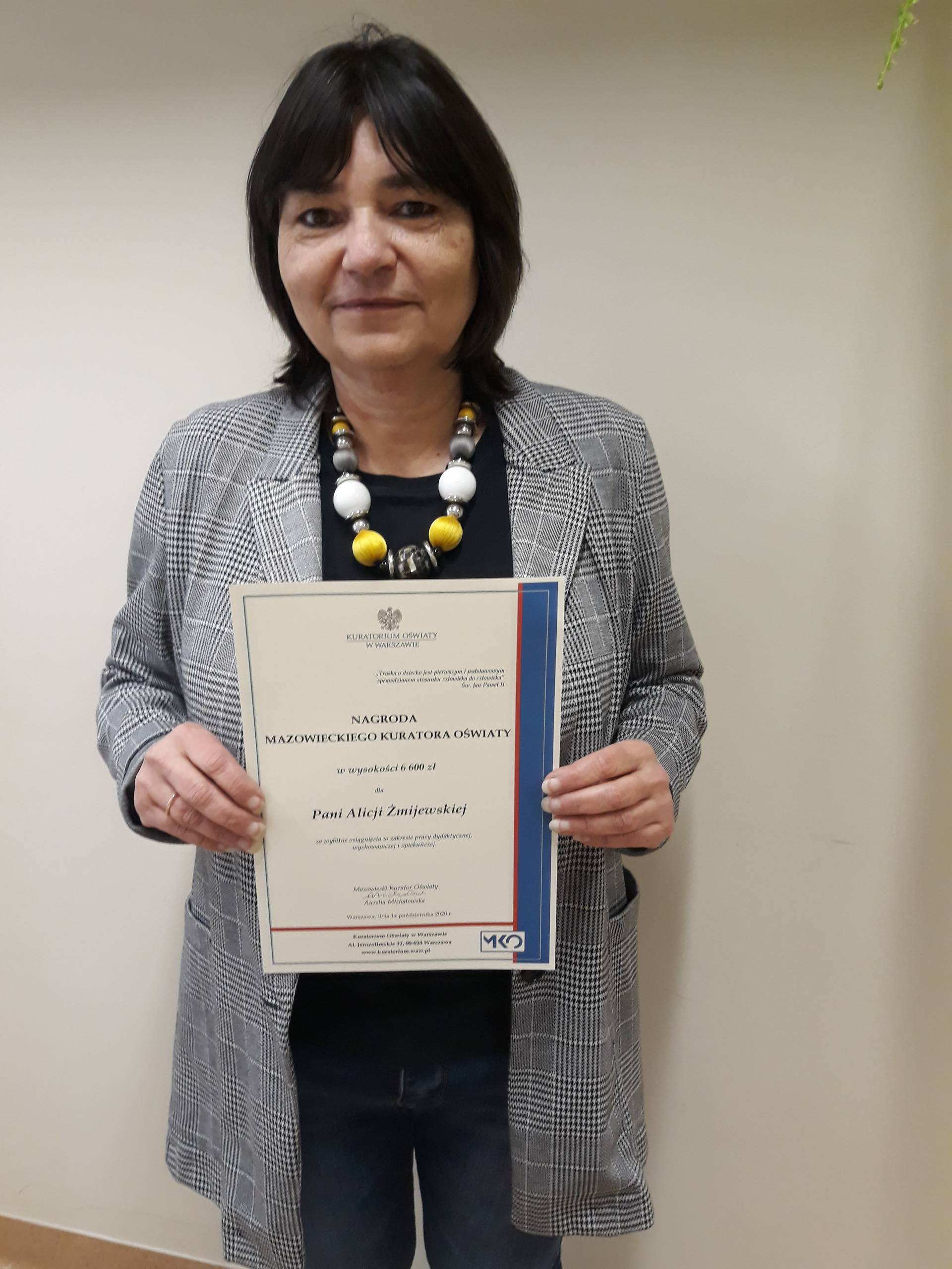 Na zdjęciu jest nauczycielka, w rękach trzyma dyplom - Nagrodę Kuratora Oświaty